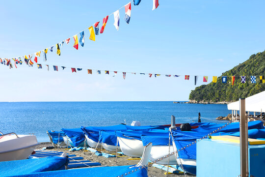 Riva Trigoso boats nautical flags Italy. Autumn coastal tranquility sea adventure mood. Mediterranean travel destination sailing guide.