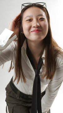 Smiling Young Asian Woman with Glasses on Head in White Shirt and Tie