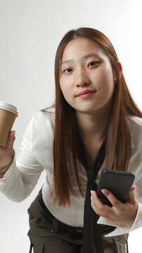 Smiling Young Asian Woman Holding Smartphone and Paper Coffee Cup