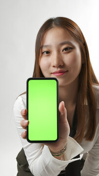 Young Asian Woman Showing Smartphone with Green Screen Mockup