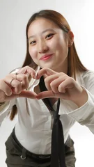 Young Asian Woman Making Heart Shape Gesture with Hands © amedeoemaja