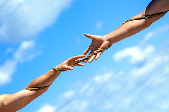 Hand holds the rope and helps the person escape. Two hands, helping hand of a friend