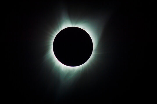 Total solar eclipse with glowing corona in dark sky