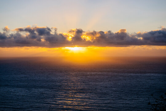 Sunset over ocean with clouds and golden sunlight