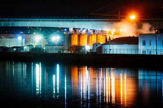 Industrial plant with illuminated storage tanks and water reflection