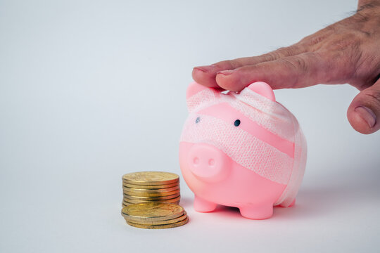 Piggy bank wrapped in a bandage on a plain background with copy space, representing financial recovery, debt relief, deposit protection, bankruptcy, business rehabilitation and a fresh start.