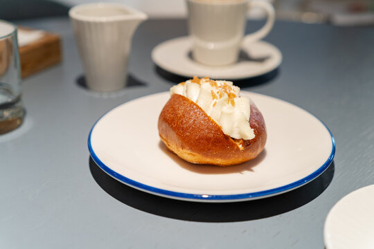 Sweet cream bun dessert with coffee cup on cafe table