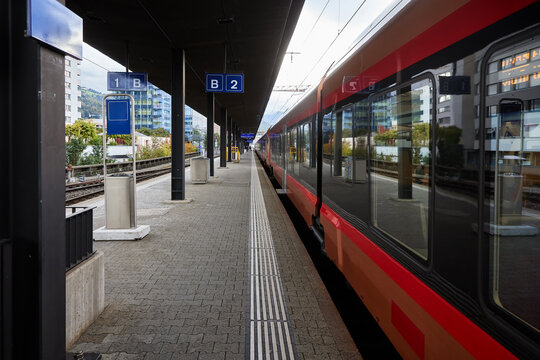 Modern passenger train standing at railway station platform outdoors. Public transport infrastructure for commuter travel, regional rail transit, and urban passenger logistics