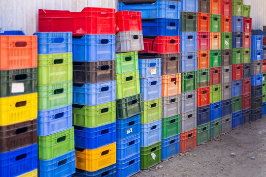 Stacked colorful plastic crates outdoors against wall logistics