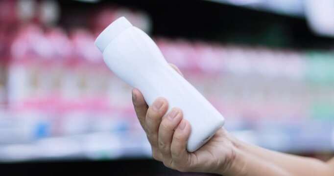 Customer holding a blank white plastic powder bottle while examining a sample product in store, Shopping in a store, Baby powder testing, Hygiene, Retail shopping, Personal care, consumer choice