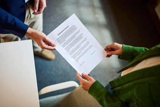 Manager hands an employment contract to a candidate in the office