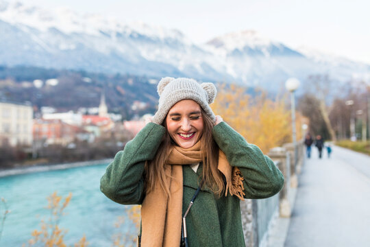 Austria, Innsbruck, portrait of young woman putting on her cap