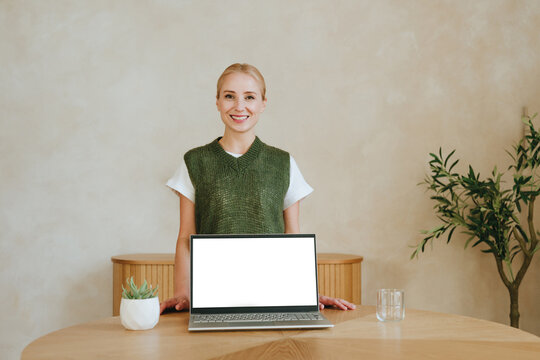 A smiling businesswoman presents a laptop with blank screen