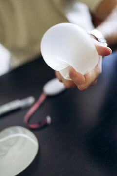 Surgeon or patient's hand squeezing a silicone breast implant, demonstrating its texture and flexibility for augmentation procedures