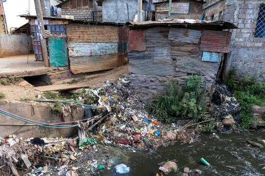 Polluted stream clogged with garbage beside tin shacks in an informal settlement, Nairobi County, Nairobi, Kenya