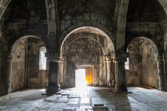 Stone arches and columns inside a medieval monastery with light from an open door, Lori Province, Haghpat, Armenia