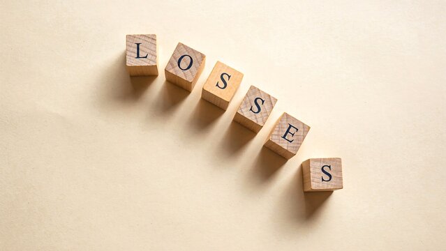 Wooden blocks spelling losses on a beige surface representing financial setbacks and business challenges