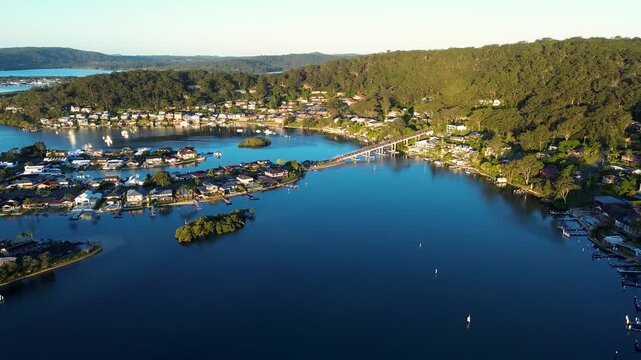 Drone aerial landscape of residential suburban homes at St Huberts Island with a connecting bridge at Daleys Point and Brisbane Water inlet surrounded by bushland forest on the Central Coast Australia