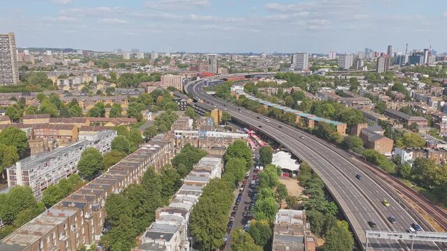 Westway A40 elevated dual carriageway and parallel railway lines curve through North Kensington, Royal Borough of Kensington and Chelsea, Greater London, England, United Kingdom, drone forward flyover