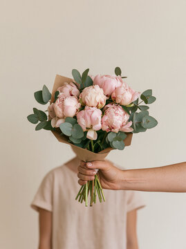 Hand Giving Beautiful Bouquet of Pink Peonies and Eucalyptus Leaves