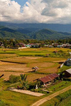 High Angle Landscape View of Rice Fields Village and Mountains Under Cloudy Sky