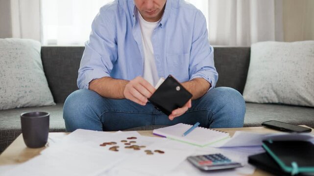 Worried man holding empty wallet counting cash money surrounded by bills. Financial stress, high living cost, rising utility expenses, inflation crisis, unpaid debt, shock. High quality 4k footage