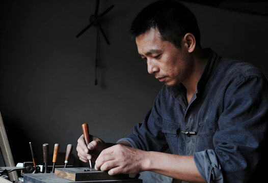 Craftsmanship and traditional skills, artisan carving wood with hand tools in a workshop, focus and dedication in manual labor and creative work