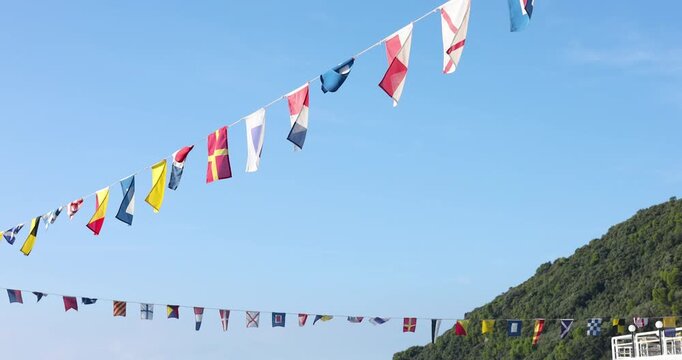 Nautical flags fluttering sea breeze Italy. Maritime celebration cheerful coastal motion mood. Mediterranean travel destination sailing guide.