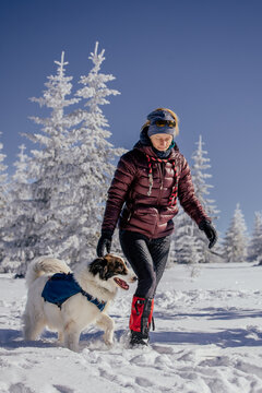 Happy woman walking the dog in a majestic winter landscape. 