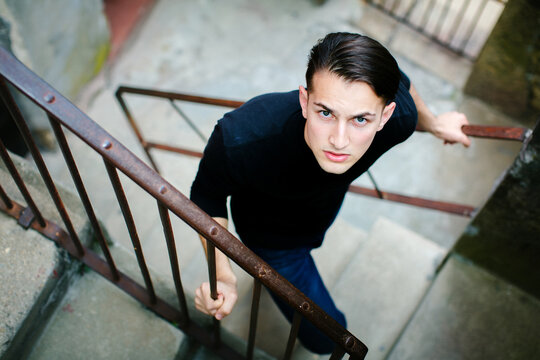 Young man climbing an outdoor staircase and looking up at the camera from a high angle