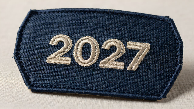 Dark blue fabric badge featuring detailed white embroidered digits representing the year two thousand twenty seven