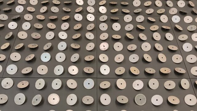 Rows of circular metal discs cover a floor display at an indoor exhibition