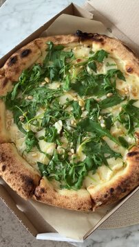 Woman taking pizza piece with cheese and arugula in paper box top view close up. Fast food snacks.