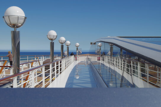 Pooldeck or swimmingpool with sun deck on modern cruiseship cruise ship liner in port with sun loungers ready for cruising to Mediterranean on sunny day with city skyline in background