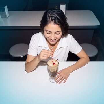 Woman sinking a straw into a root beer float at a diner counter
