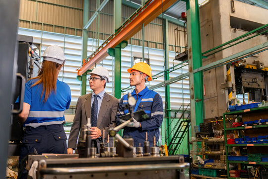 Industrial manager and factory engineer inspecting machinery control panel in manufacturing plant, Engineering team and supervisor holding clipboard during machine inspection in manufacturing workshop