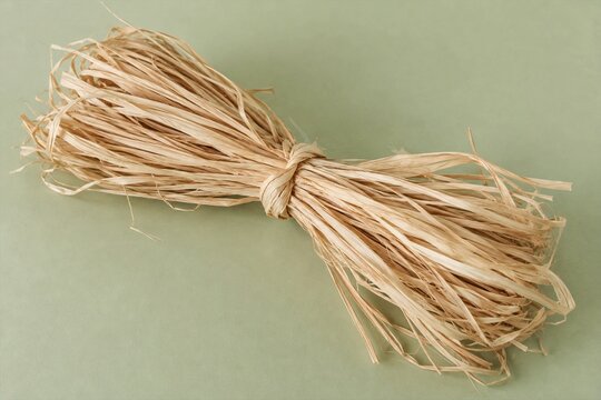 Bundle of natural raffia fiber tied on a pale green surface