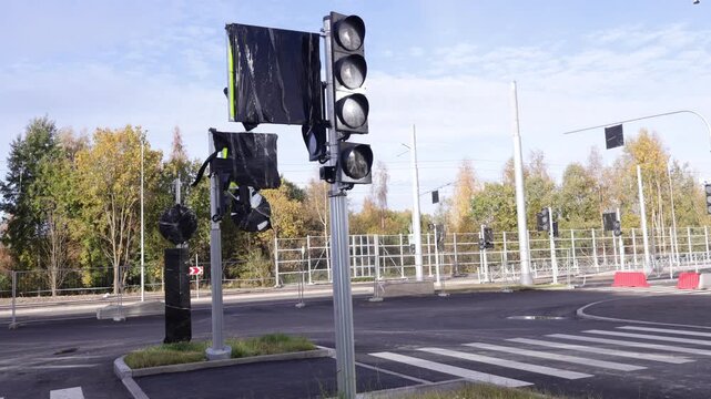 Urban intersection features multiple traffic light units with protective black casings