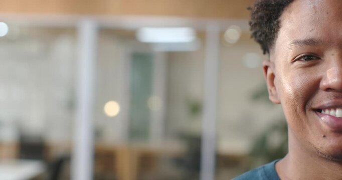 African American man reacting to off-camera prompt, smiling in office by glass divider, copy space