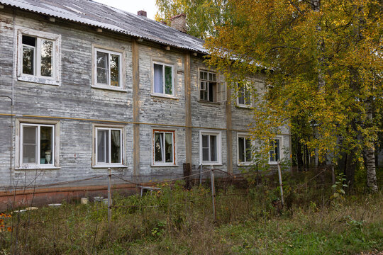 The facade of two-story wooden residential house surrounded by colorful autumn nature in a provincial town of Russia.