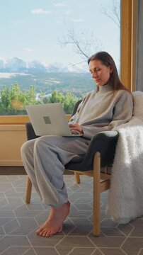 A woman using laptop and enjoying scenic snowy mountain view.