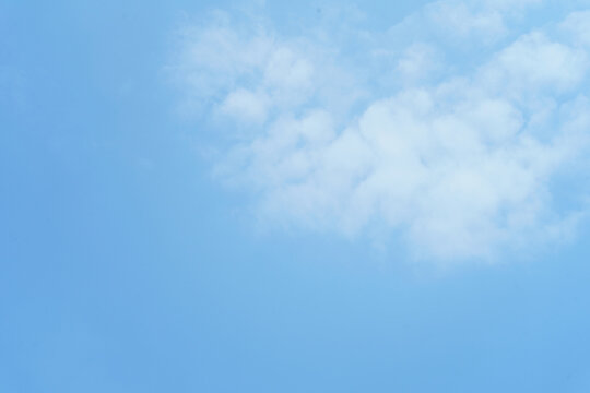 White fluffy cloud on clear blue sky background. Clean minimalist sky background with copy space for text or design.