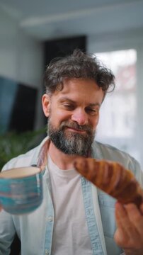 A man enjoying a fresh croissant and coffee for breakfast