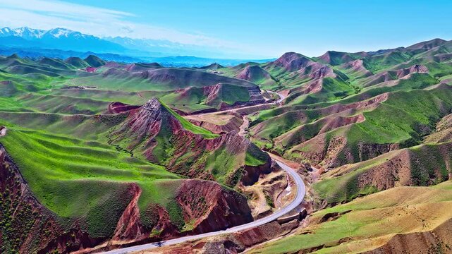Aerial view of a scenic winding road through colorful Danxia landforms along S101 highway in Xinjiang, China.