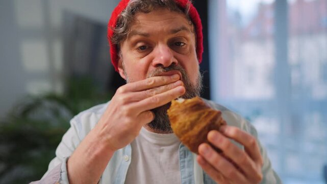 A man enjoying a fresh croissant for breakfast. Slow motion