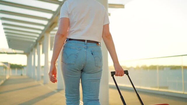 Woman confidently pulling a suitcase in an airport terminal. Back view