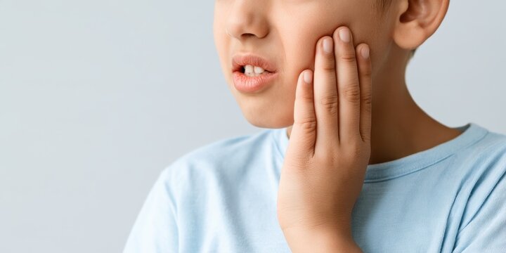 Boy holding his cheek with toothache against a light background
