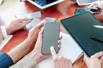 Diverse coworkers' hands using smartphones and tablet around a meeting table © Rawpixel.com