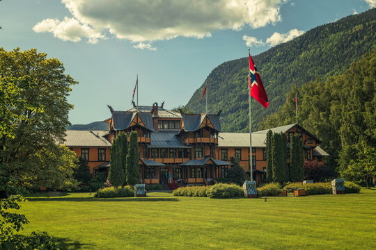 Dalen, Tokke, Norway - 16.06.2026: Ornate wooden Dragestil architecture hotel with flags on a lush green lawn against forested mountains