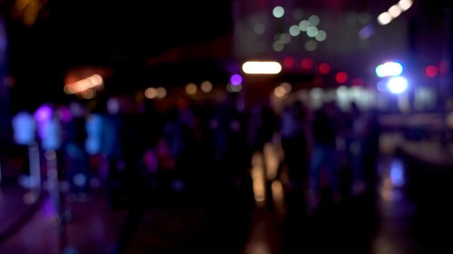 Defocused crowd of people walking at a night event, blue and red lights glowing as round bokeh, intentionally out of focus
